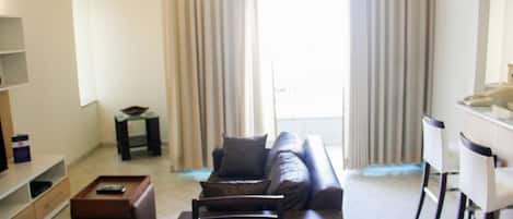 A living room with a sofa, a coffee table, and a dining area with chairs.