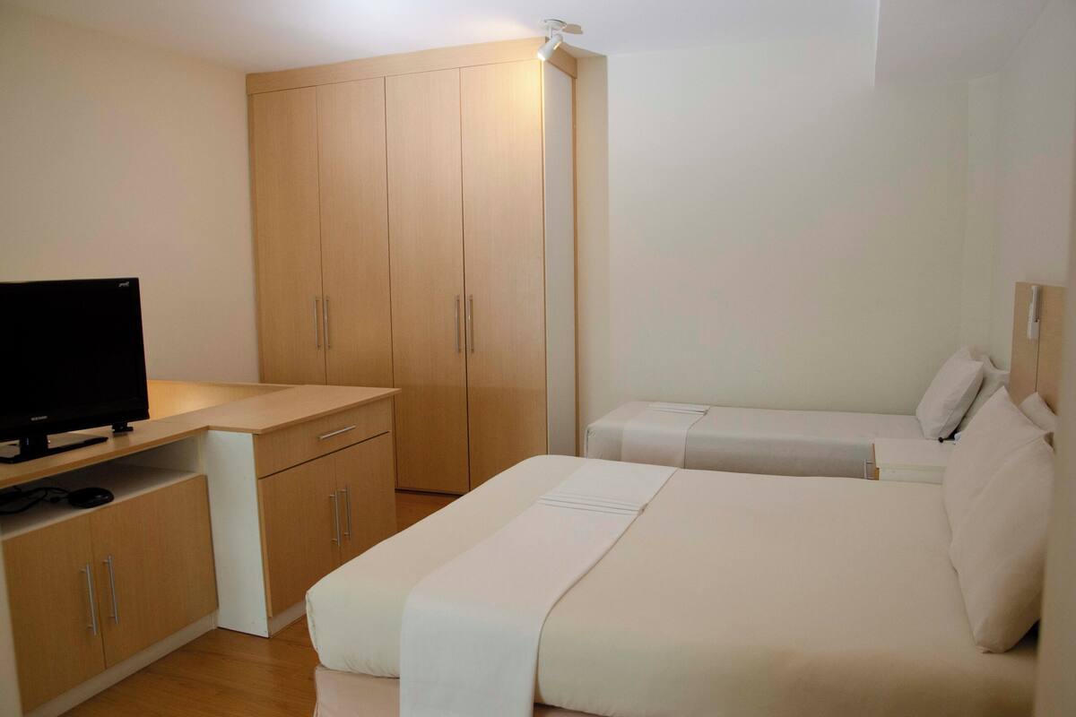 A hotel room with a bed, a TV, and a wardrobe.