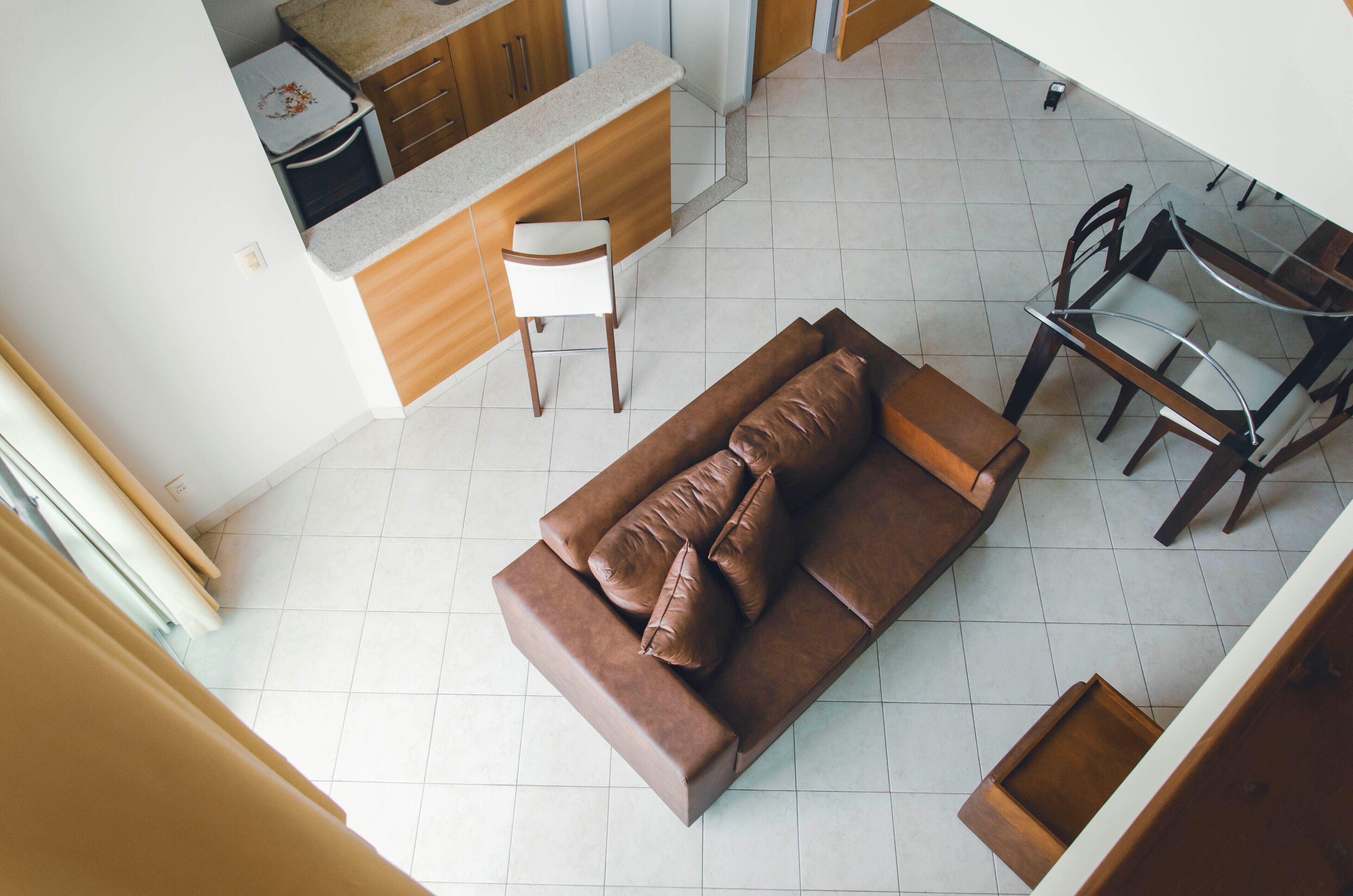 Una sala de estar moderna con un sofá marrón, una mesa de comedor con sillas y una cocina al fondo.