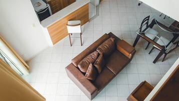 Una sala de estar moderna con un sofá marrón, una mesa de comedor con sillas y una cocina al fondo.
