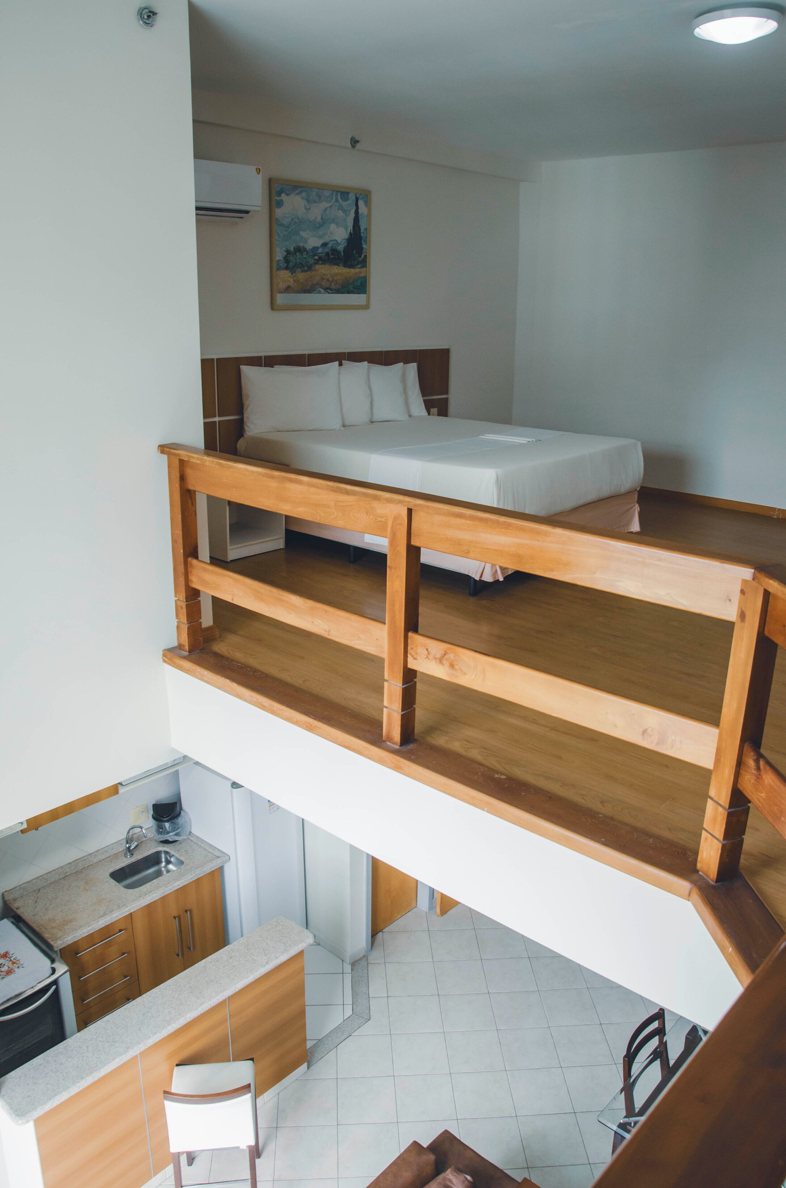A room with a bunk bed, a desk with a chair, and a small kitchenette.