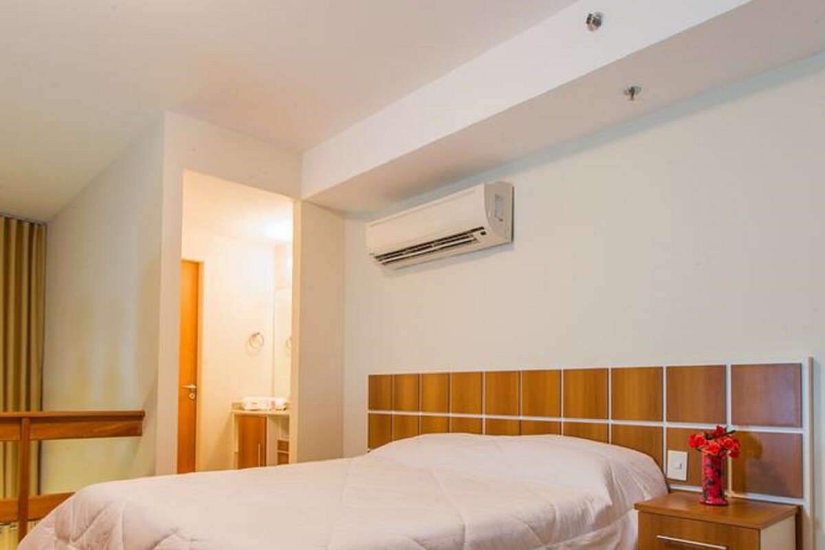 A bedroom with a bed, bedside table, and an air conditioning unit.