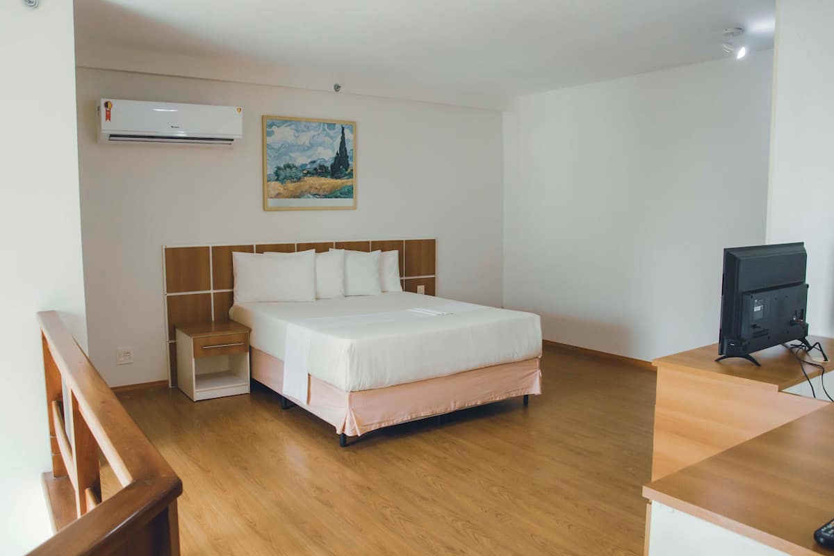 A bedroom with a bed, bedside table, and a TV.