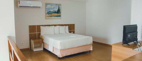 Een slaapkamer met een bed, nachtkastje en een televisie.