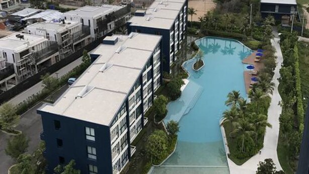 A resort with a large pool area, including a slide, surrounded by buildings and a view of the sea. - Baan Thew Talay Blue Sapphire 353 (Cha-am)