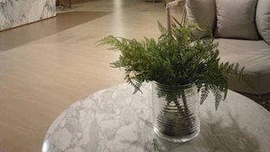 A modern lobby with a marble reception desk, wooden slatted wall, seating area with sofas and tables, and large windows. - Baan Thew Talay Blue Sapphire 353 (Cha-am)