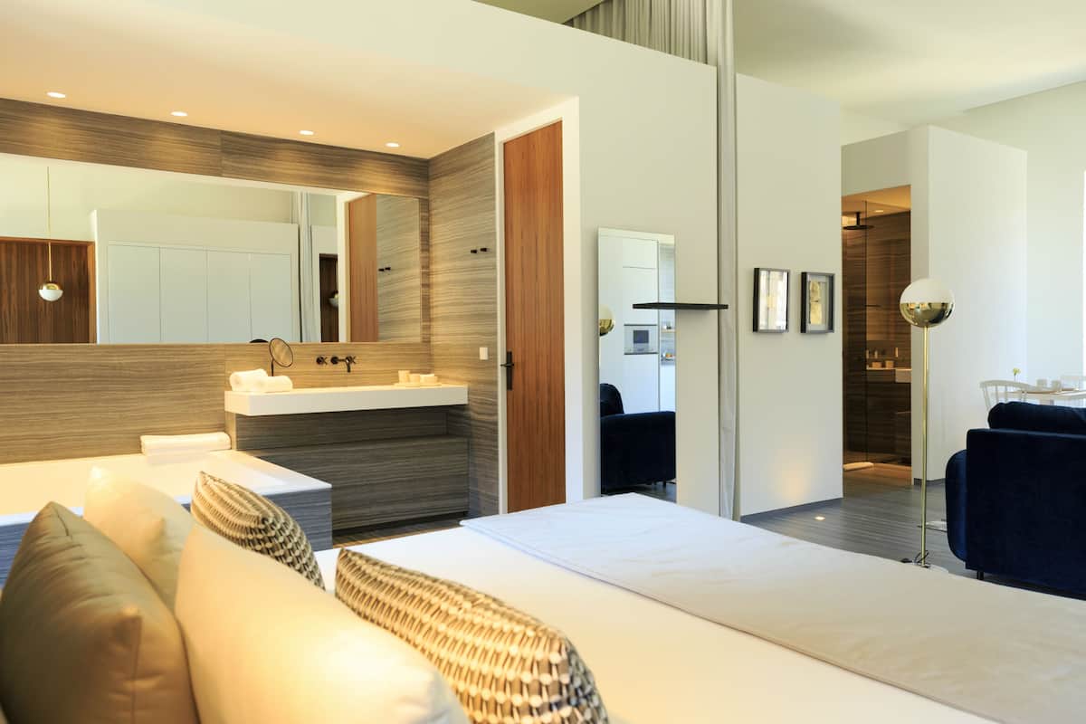 A modern bedroom with a large bed, bedside tables, a built-in vanity, and a mirror.