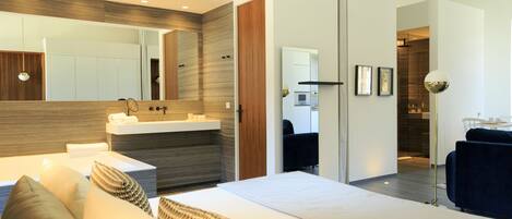 A modern bedroom with a large bed, bedside tables, a built-in vanity, and a mirror.