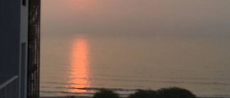 A sunset over a body of water with a path leading to the water's edge.
