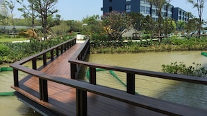 Un pont en bois enjambant une étendue d’eau, avec un bâtiment moderne en arrière-plan.