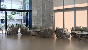 Un espace intérieur vaste et lumineux, aménagé avec des meubles en osier, de grandes fenêtres et offrant une vue sur la verdure environnante.