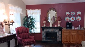 A living room with a fireplace, a red armchair, a coffee table, and a large plant.