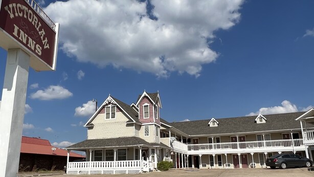 Victorian Inns with a two-story building, a balcony, and a signboard.