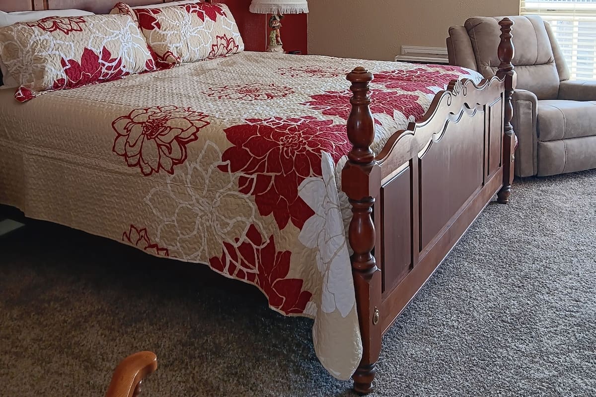 A bedroom with a large bed, a chair, and two framed pictures on the wall.