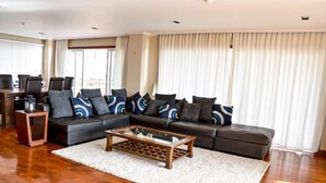 A modern living room with a sectional sofa, a glass coffee table, and a wooden side table.