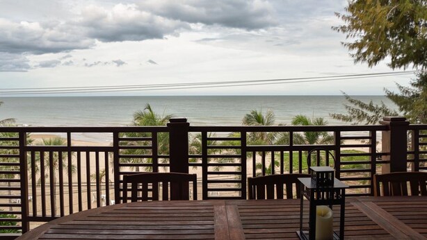 A wooden deck with a view of the beach and ocean.