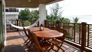 A wooden table and chairs on a balcony with a view of the sea.