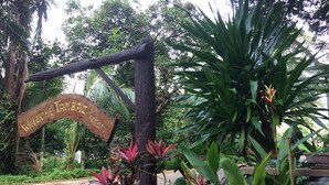 Un letrero de madera con la inscripción 'Welcome to Tambal Resort', rodeado de exuberante follaje y plantas.