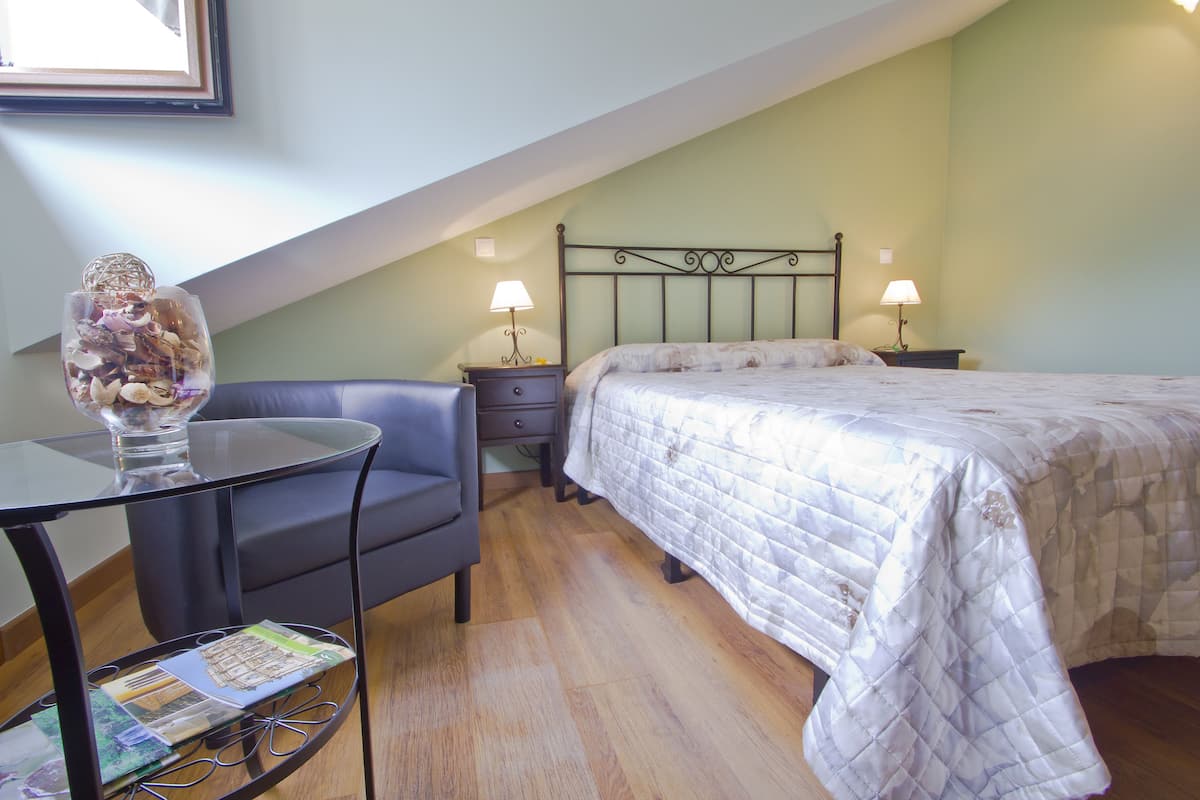A bedroom with a bed, nightstands, a table with a vase, and a chair.