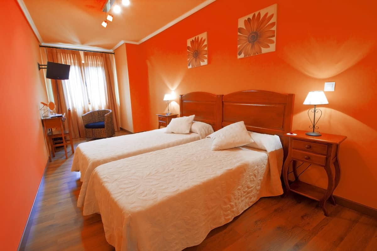 A hotel room with two beds, a TV, a desk, and a chair.