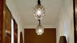 A hotel room with a bed, two wall-mounted lamps, a floor lamp, and a wooden chair. - Riad Tzarra (Marrakech)