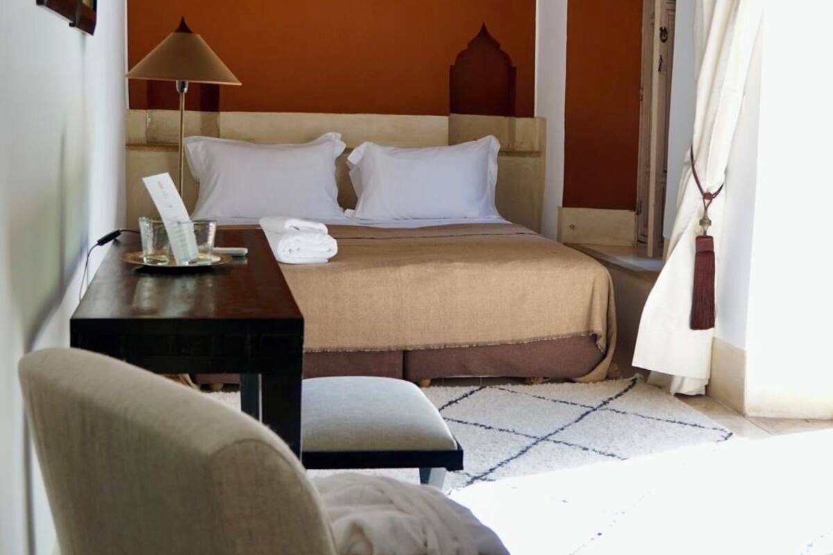 A bedroom with a bed, a desk, a chair, and a lamp.
