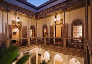 Un patio con balcones de madera ornamentados, arcos y luminarias decorativas.