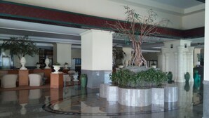 A spacious lobby with a central fountain, white columns, and various potted plants. - Cha-Am Grand Condotel (Cha-am)