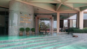 A grand entrance with a stone pillar, steps leading up to a glass door, and potted plants. - Cha-Am Grand Condotel (Cha-am)