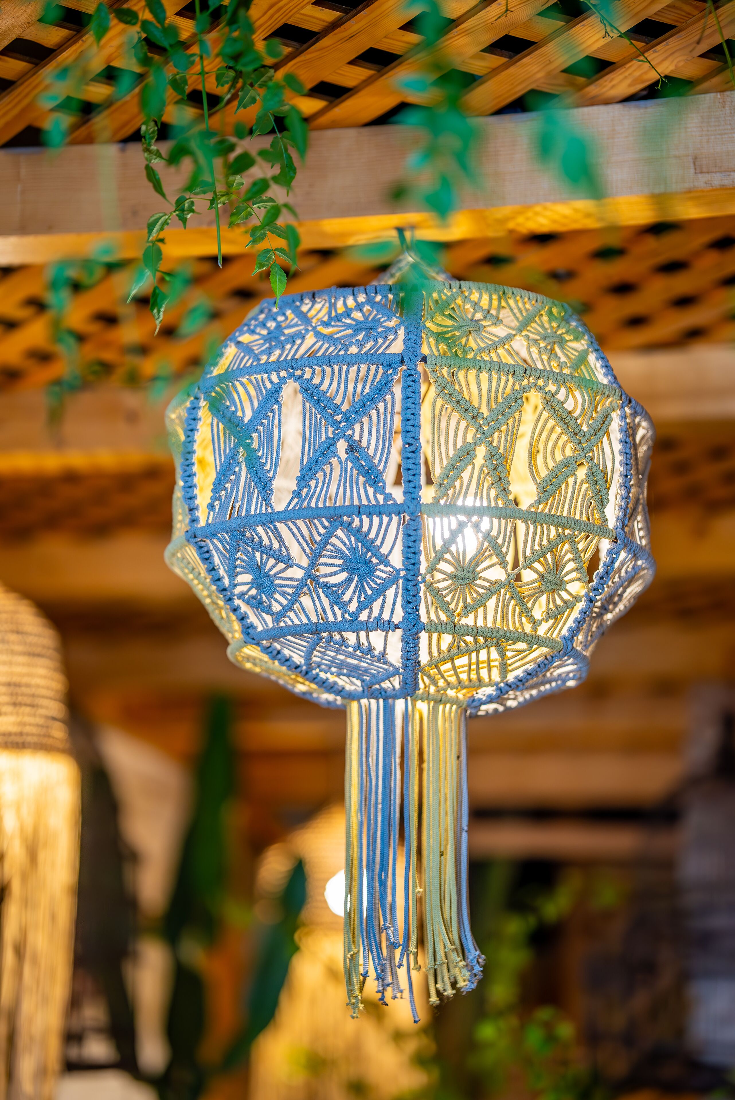 Un luminaire décoratif suspendu, orné d’un motif géométrique, fixé à une structure en bois au plafond.
