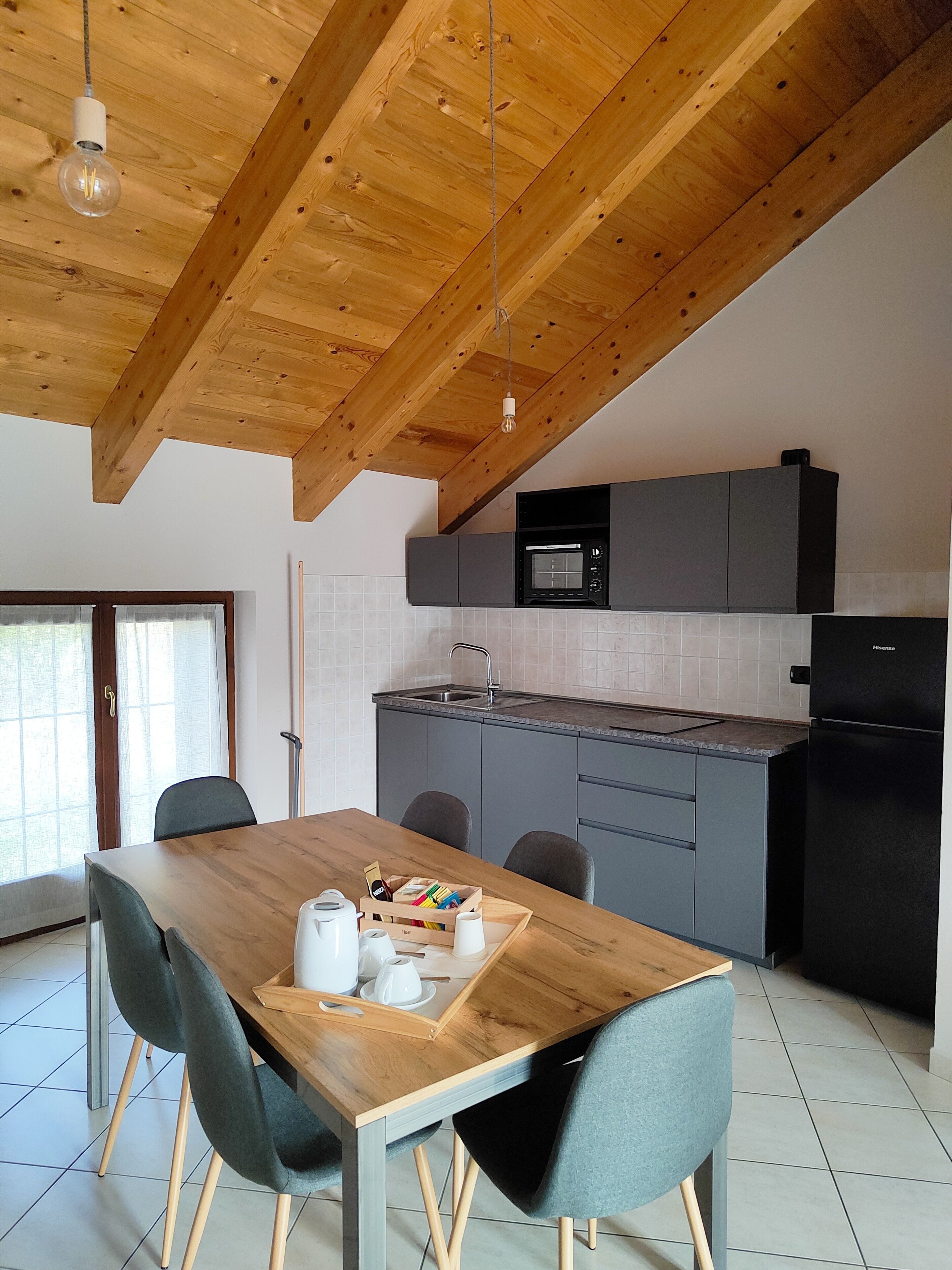 A modern kitchen with grey cabinets, a black refrigerator, and a built-in microwave.
