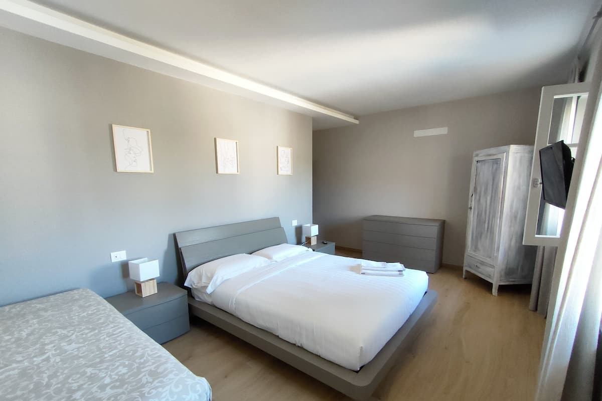Een slaapkamer met een bed, nachtkastjes, een dressoir en een kledingkast.