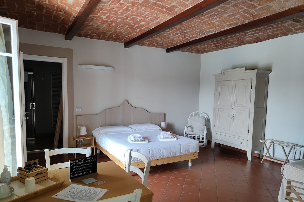 Een kamer met een bed, een houten bureau, een stoel, een kledingkast en een deur naar een badkamer.