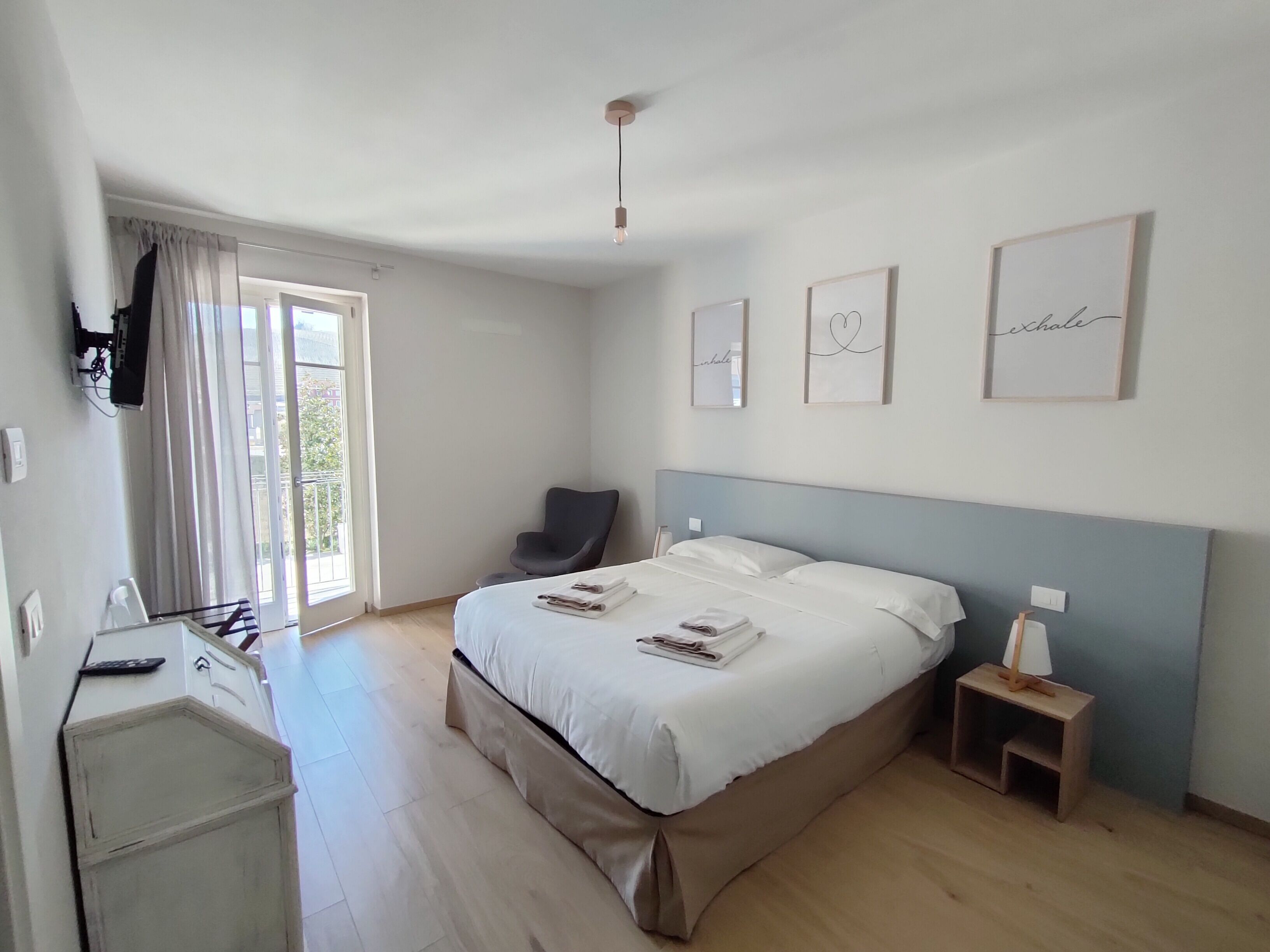 A bedroom with a bed, a chair, a desk, and a window.