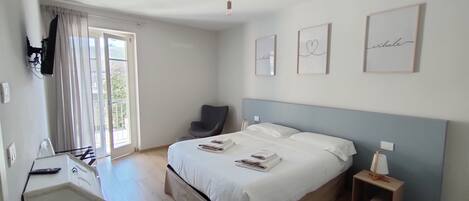 A bedroom with a bed, a chair, a desk, and a window.