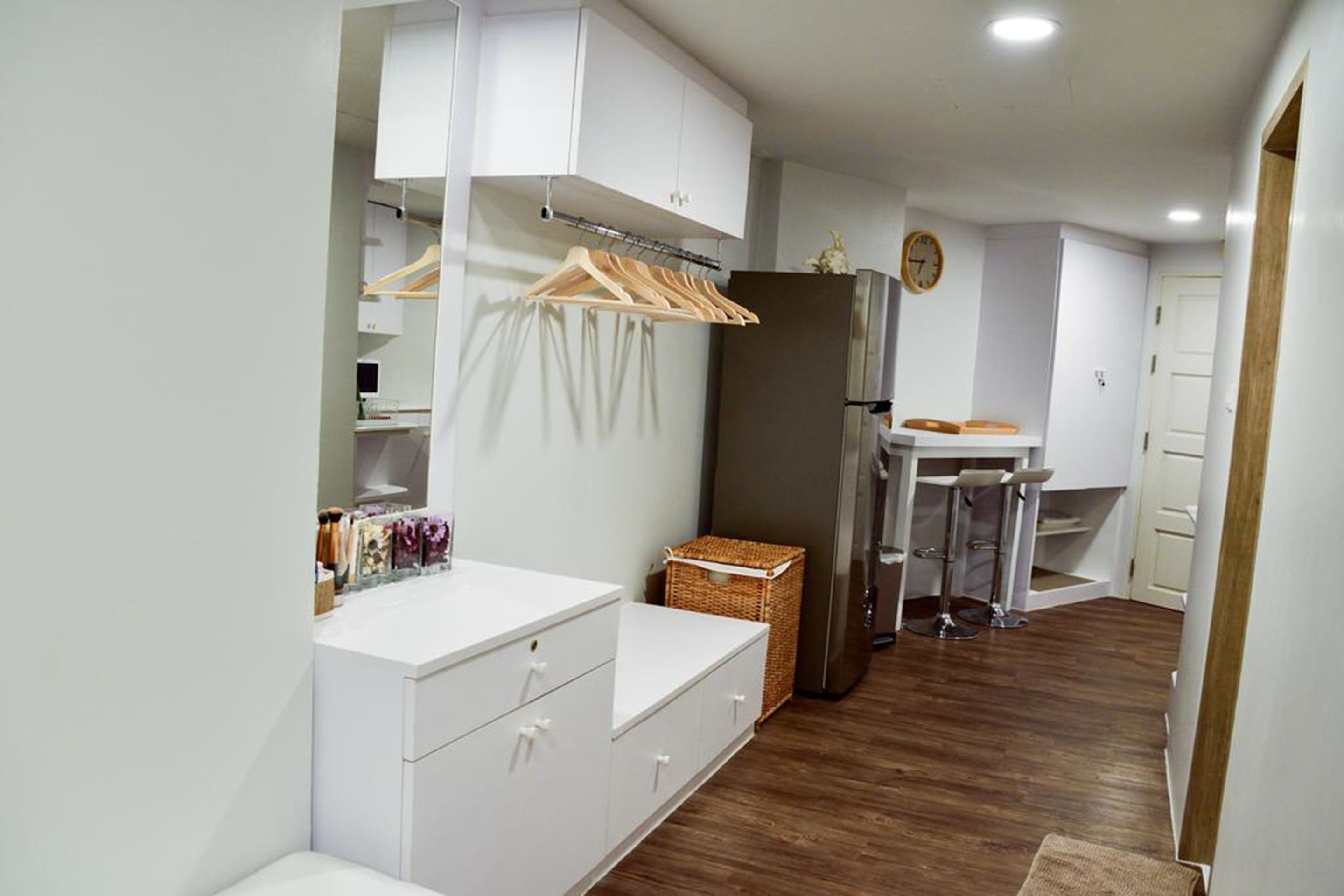 A modern kitchen with white cabinets, a wooden countertop, and a stainless steel refrigerator.