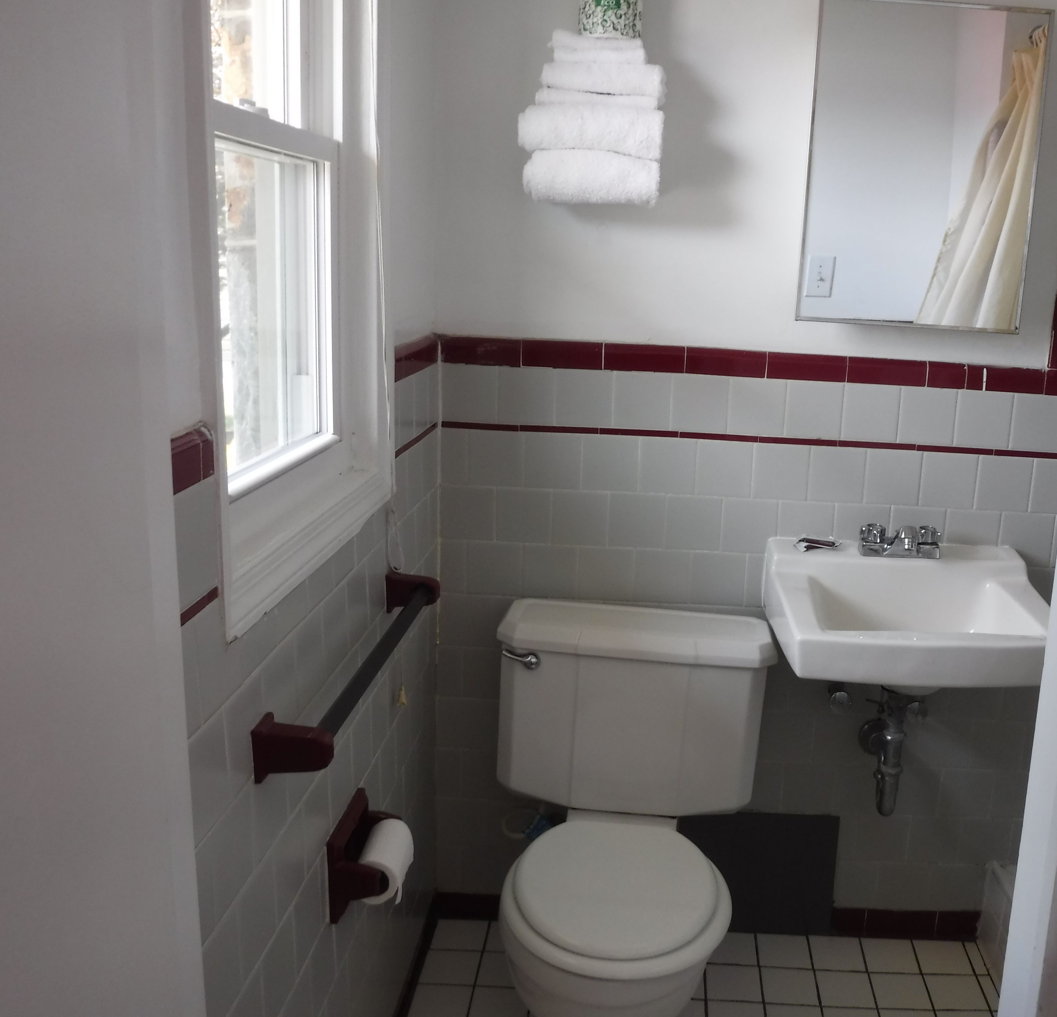 A small bathroom with a toilet, sink, and a window.