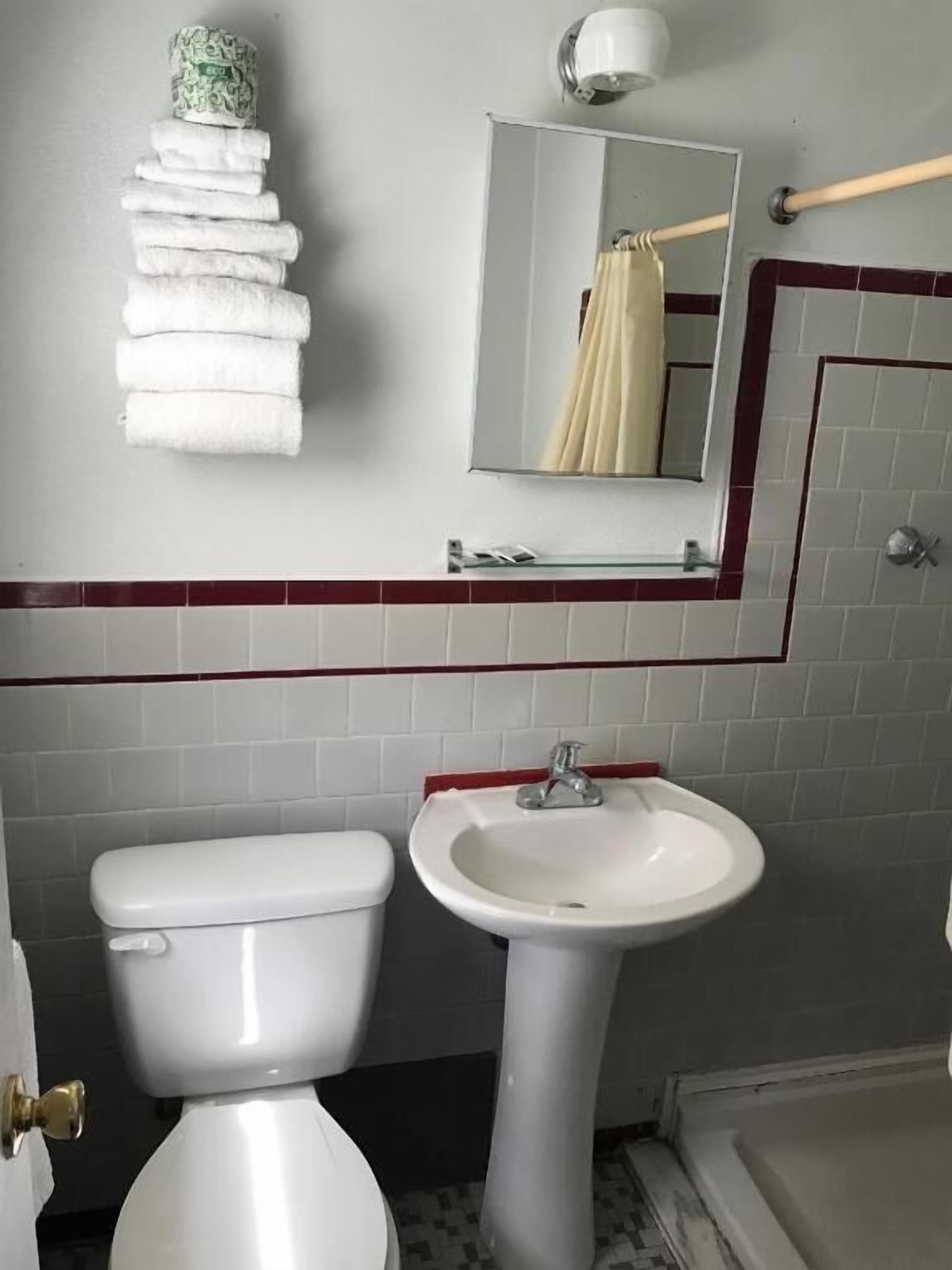 Kylpyhuone, jossa on wc, pesuallas ja pyyheteline, jossa on siististi taiteltuja pyyhkeitä.
