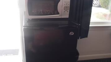 A black refrigerator with a microwave on top, a window with a curtain, and a date stamp of 7/21/2017.