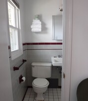 A small, compact bathroom with a toilet, sink, and a towel rack.