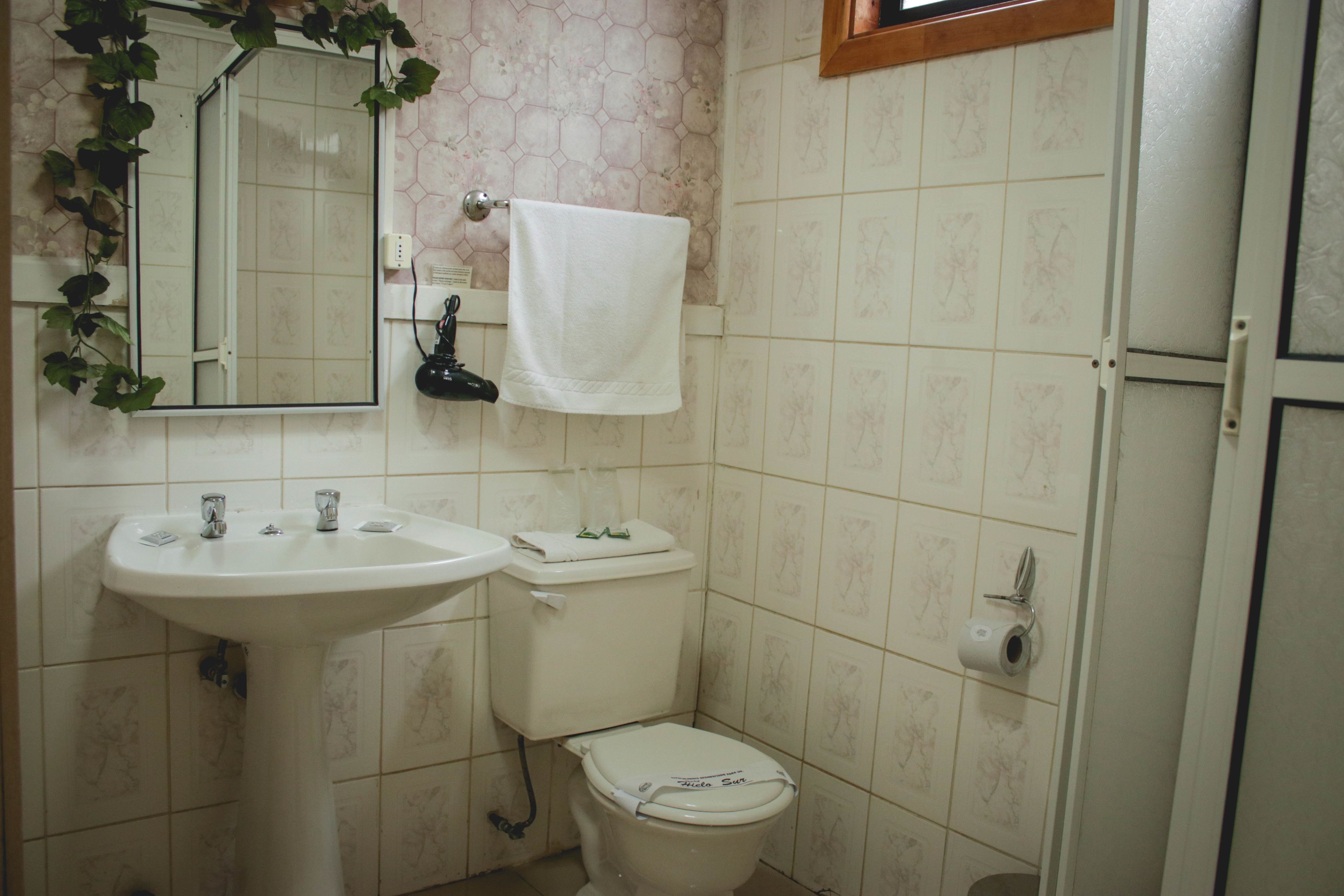 Un baño con lavamanos, inodoro y espejo.