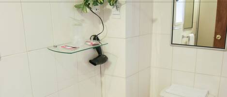 A bathroom with a white sink, toilet, and a glass shelf with toiletries.