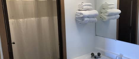 A bathroom with a shower, toilet, sink, and towels.