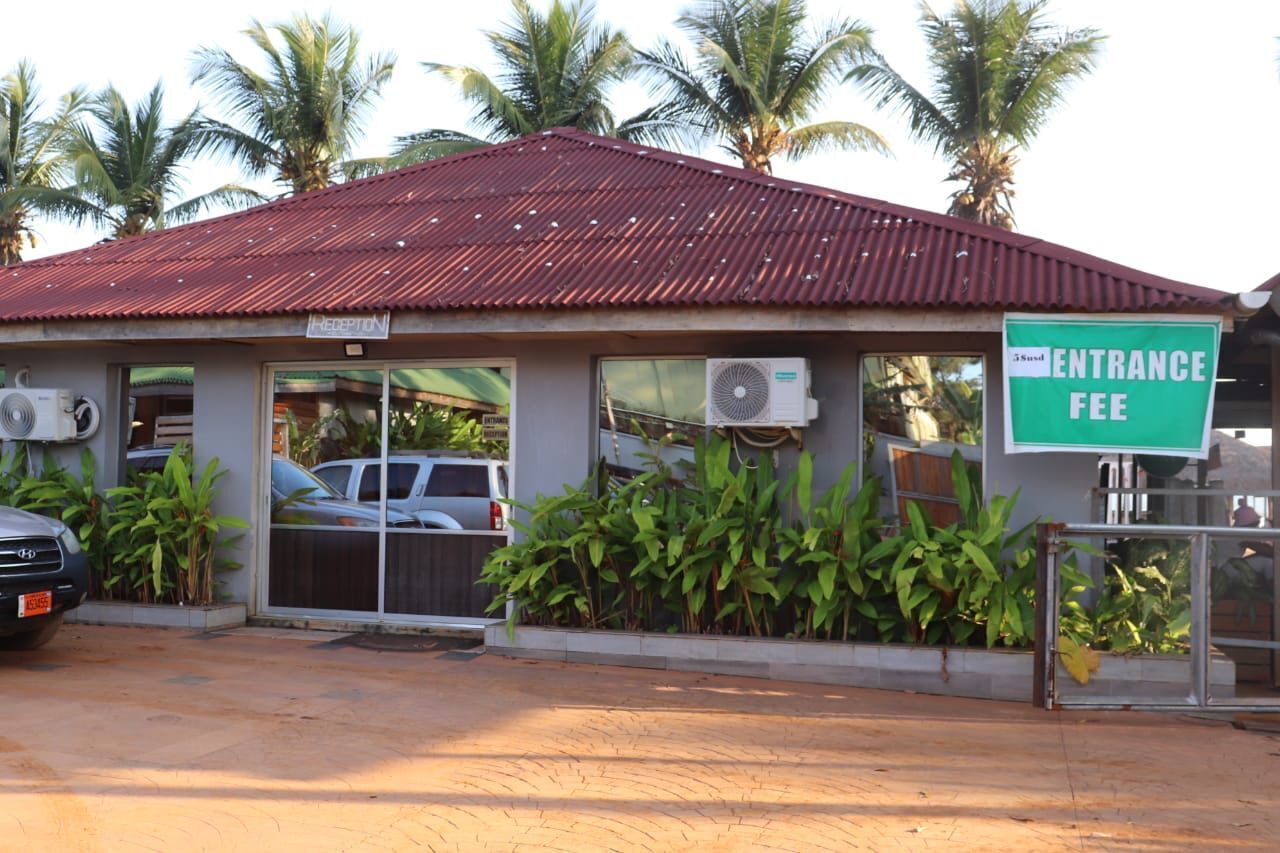 A building with a red roof, an entrance fee sign, and air conditioning units.