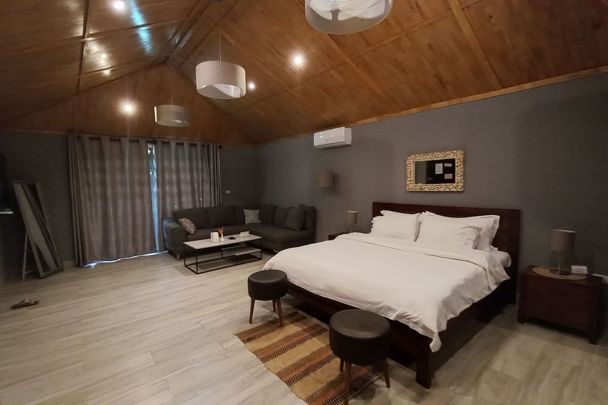 A modern bedroom with a large bed, a sofa, a coffee table, and a TV.