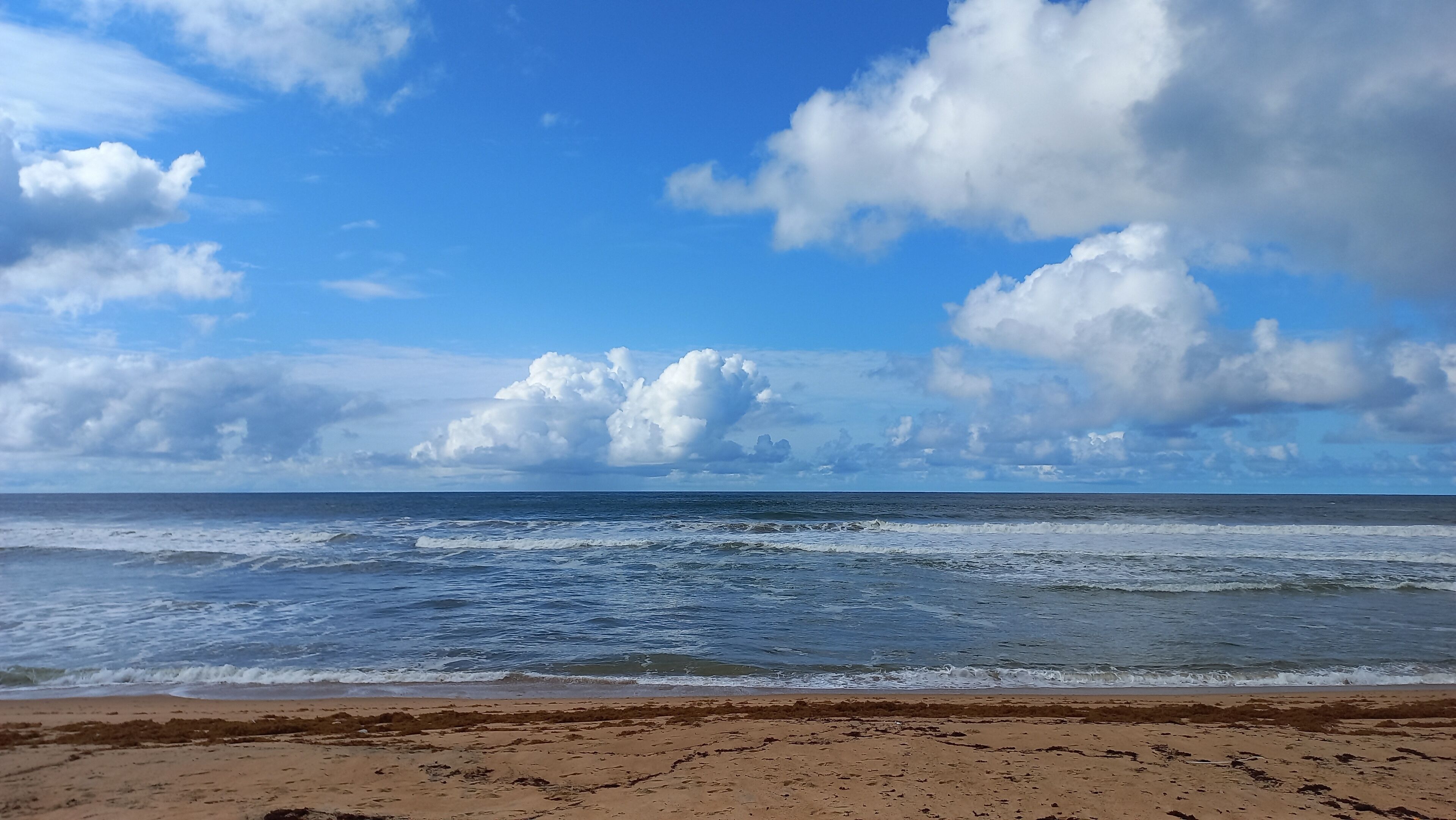 A beach with waves and a clear sky.