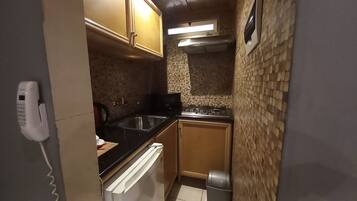 Una cocina compacta con estufa, fregadero y armarios.
