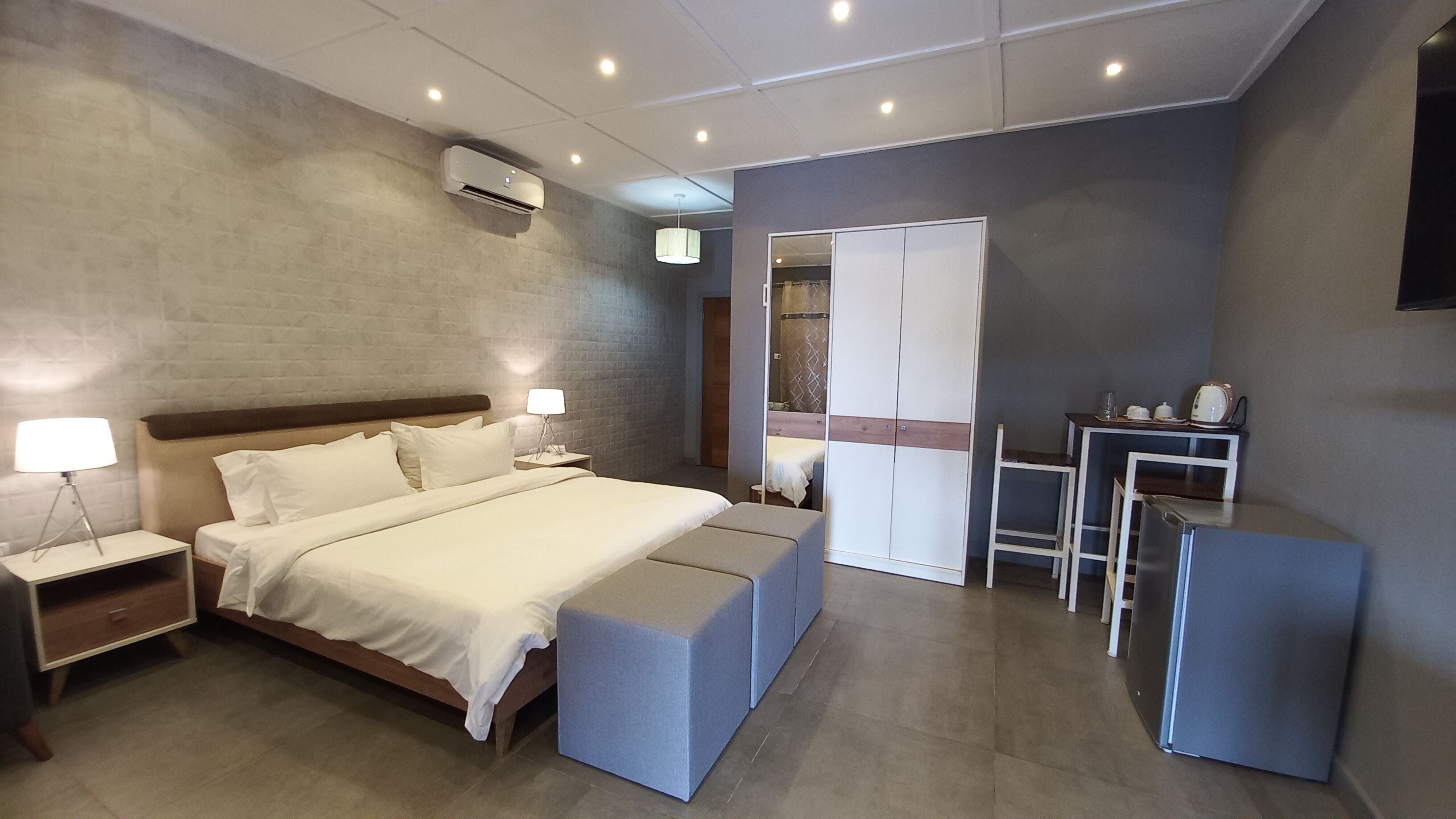 Una habitación de hotel moderna con una cama grande, mesitas de noche, un escritorio y un armario.