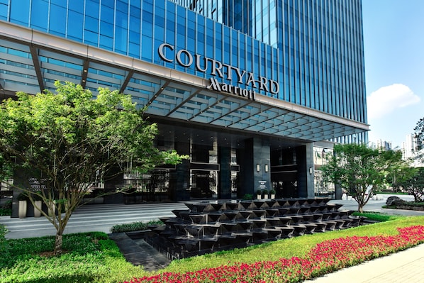 A Courtyard Marriott hotel with a modern glass facade, a landscaped entrance with a water feature, and a clear sky. - Courtyard by Marriott Changsha South (Changsha)