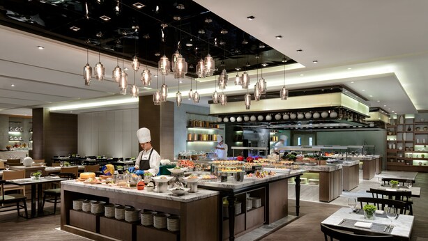 Um restaurante moderno com ilha central, várias mesas de jantar e luminárias pendentes.